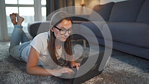 Woman is lying on the floor and and makes an online purchase using a credit card and laptop. Online shopping, lifestyle