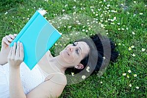 Woman lying on a flowered meadow reading a book