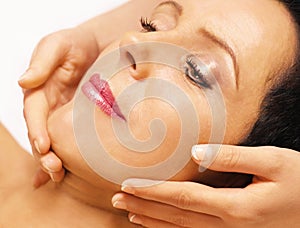 Woman lying, gets massage, reiki, on her face