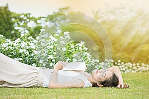 Asian woman lying grass field after she tired for reading a book in the afternoon