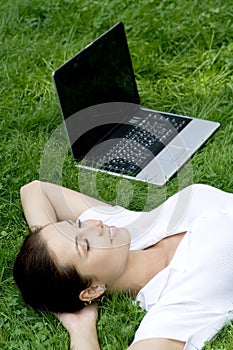 Woman lying on grass with laptop