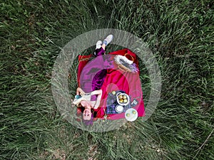 A Woman Lying On Grass With A Picnic Basket, Overhead
