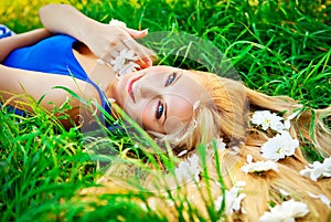 Woman lying in green grass with a flowers in hairs