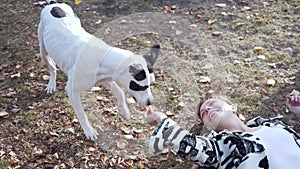 Woman lying on the ground and play with her stafford dog.