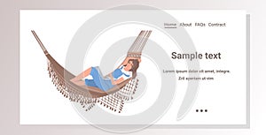 Woman lying in hammock using laptop working at home during coronavirus quarantine self-isolation concept