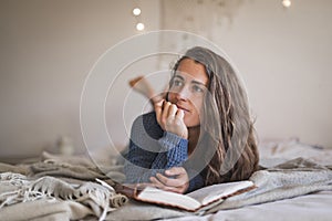 Woman lying on her bed thinking about what to write in her journal