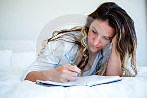 woman lying in her bed writing in a book