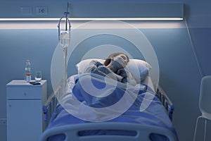 Woman lying in the hospital bed and sleeping with IV drip