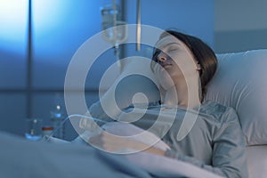 Woman lying in the hospital bed and sleeping with IV drip