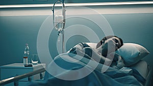 Woman lying in the hospital bed and sleeping with IV drip