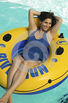 Woman lying on inflatable raft in swimming pool elevated view.