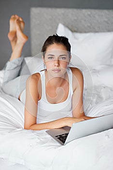 Woman, lying and laptop on bed in portrait for connection, typing and chatting online to relax. Female person