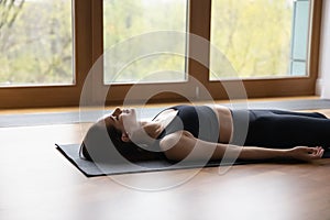 Woman lying on mat doing Corpse or Dead Body asana