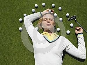 Woman Lying On Putting Green With Golf Balls