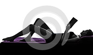 Woman lying reading book in bed silhouette