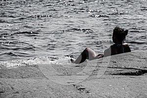 Woman lying on a rock in the ocean looking out at the horizon