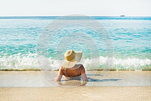 Woman lying on sand and enjoying clear blue sea waters