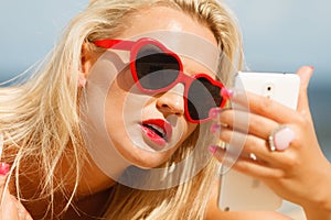 Woman lying on sandy beach using cell phone