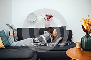 Woman Lying On A Sofa With A Notebook and phoning
