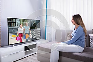 Woman Lying On Sofa Watching Television