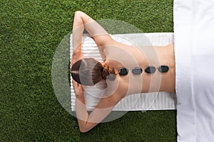 Woman lying with spa stones on back