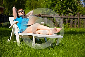 Woman lying in sun lounger and looking on laptop