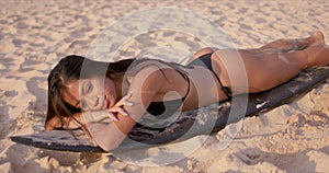 Woman lying on surfboard and sunbathing on beach