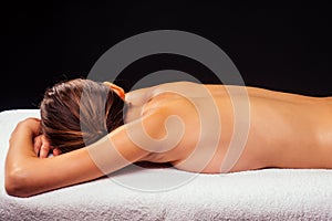 Woman lying on the table and getting ayurvedic massage with organic oil or honeyed in dark room.massagist making yoga