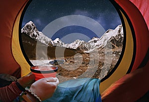 Woman lying in a tent with coffee ,view of mountains and night s