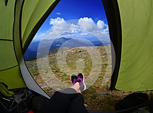 Woman lying in tent with a view of mountain and sky