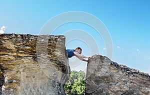 Woman lying on top of a high sandstone rock formation lying over the edge.