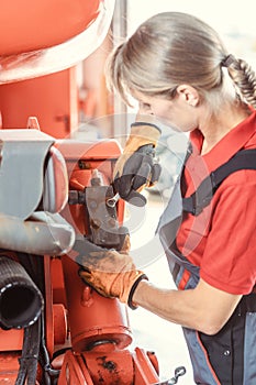 Woman machinist working with wrench of a farm machine