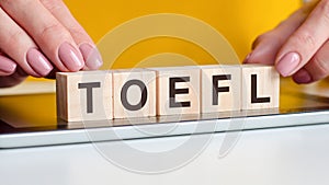 Woman made word TOEFL with wooden blocks, business concept