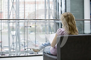 Woman With Magazine Sitting On Sofa In Shopping Mall