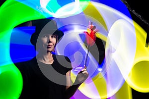 Woman magician in a black hat against a background of multi-colored light. Magic, sorcery, horoscope concept