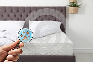 Woman with magnifying glass detecting bed bugs on mattress, closeup.