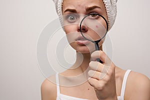 woman with a magnifying glass in hand skin problems close-up