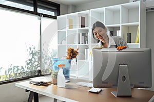 Woman maid cleaning and wiping the computer with microfiber cloth in office