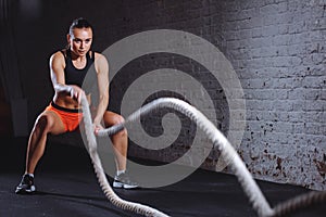 Woman make exercise with battle rope in functional training gym