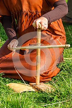 Woman make a fire with a bow drill