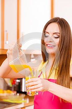 Woman make orange juice in juicer machine pouring drink in glass