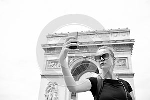 Woman make selfie with phone at arc de triomphe in paris, france. Woman with smartphone at arch monument. Vacation and