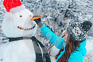 Woman make a snowman in frosty winter day