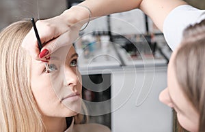 woman make up artist applying eyeshadows with brush on model eyes. blond woman face. Hand of visagiste, painting