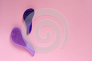 Woman make up equipment with copyspace. Plastic purple hairbrushes for combing hair on pink background