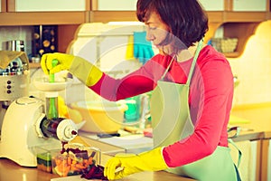Woman make vegetables juice in juicer machine photo