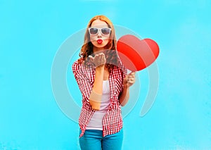 Woman makes an air kiss with a red balloon in the shape of a heart