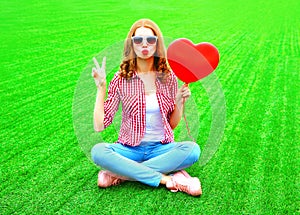 woman makes an air kiss with red balloon in the shape of a heart