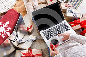 Woman makes christmas shopping online with laptop, above view