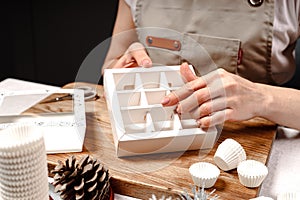 A woman makes handmade candy boxes. Close-up of female hands